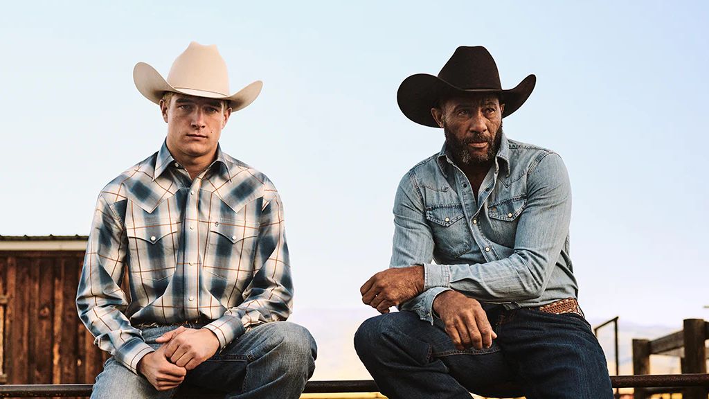 Western Wear: Two Cowboys sitting on a fence wearing Stetson hats, Western shirts, jeans and boots