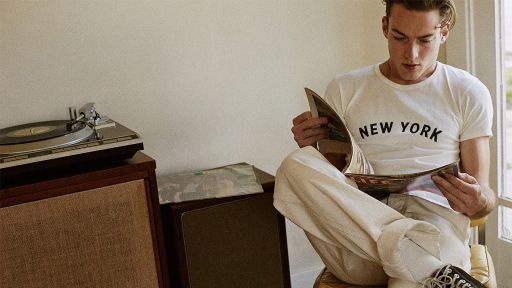 Knickerbocker MFG. Co.: A stylish man engrossed in reading a magazine while enjoying the music from a record player.